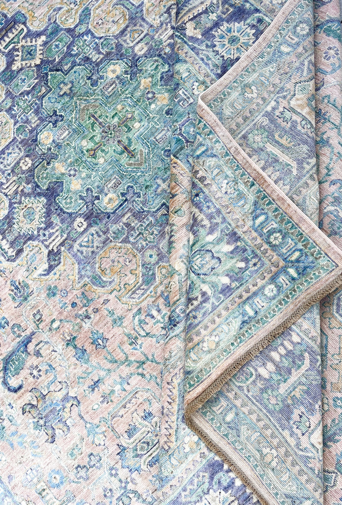 Folded blue and pink handmade Afghan rug with an ornate pattern