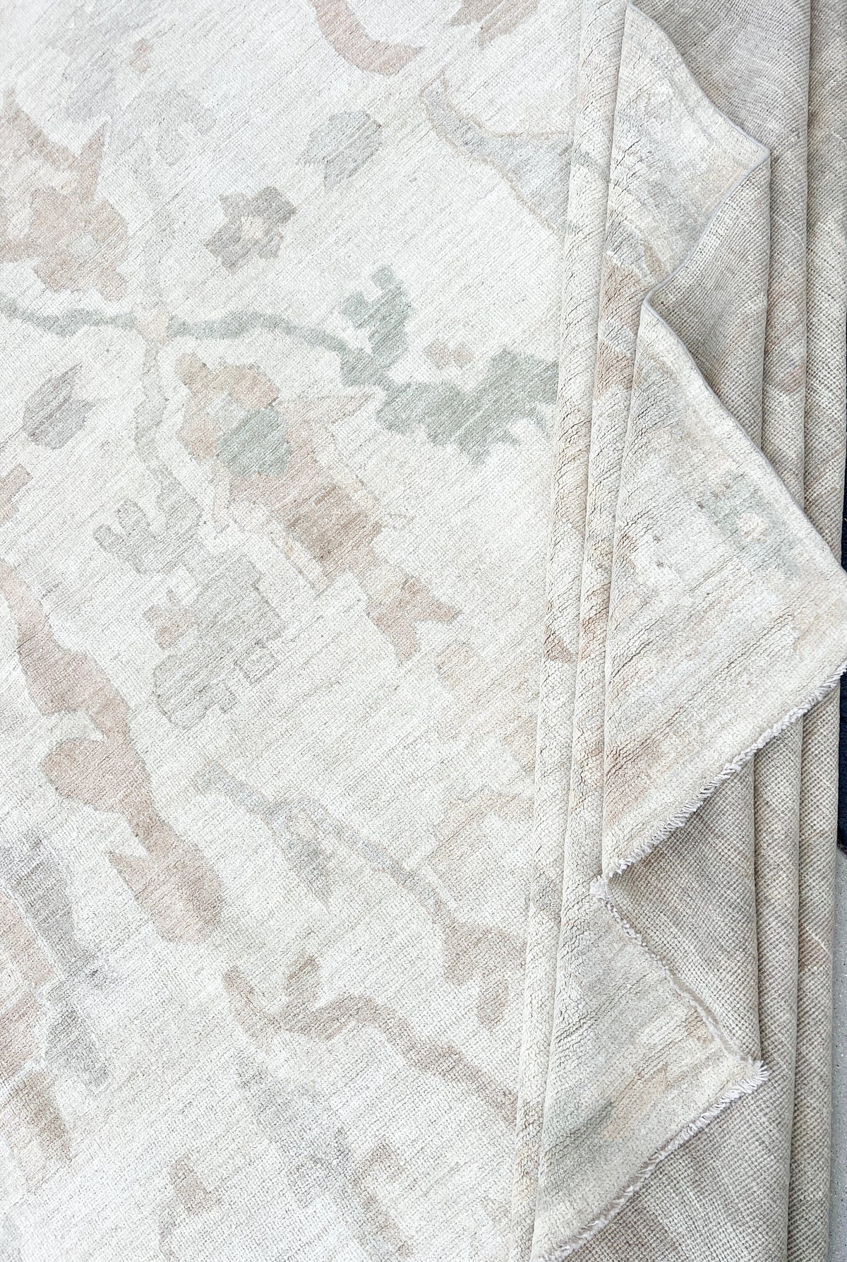 Folded ivory handmade Afghan wool rug with a subtle floral pattern