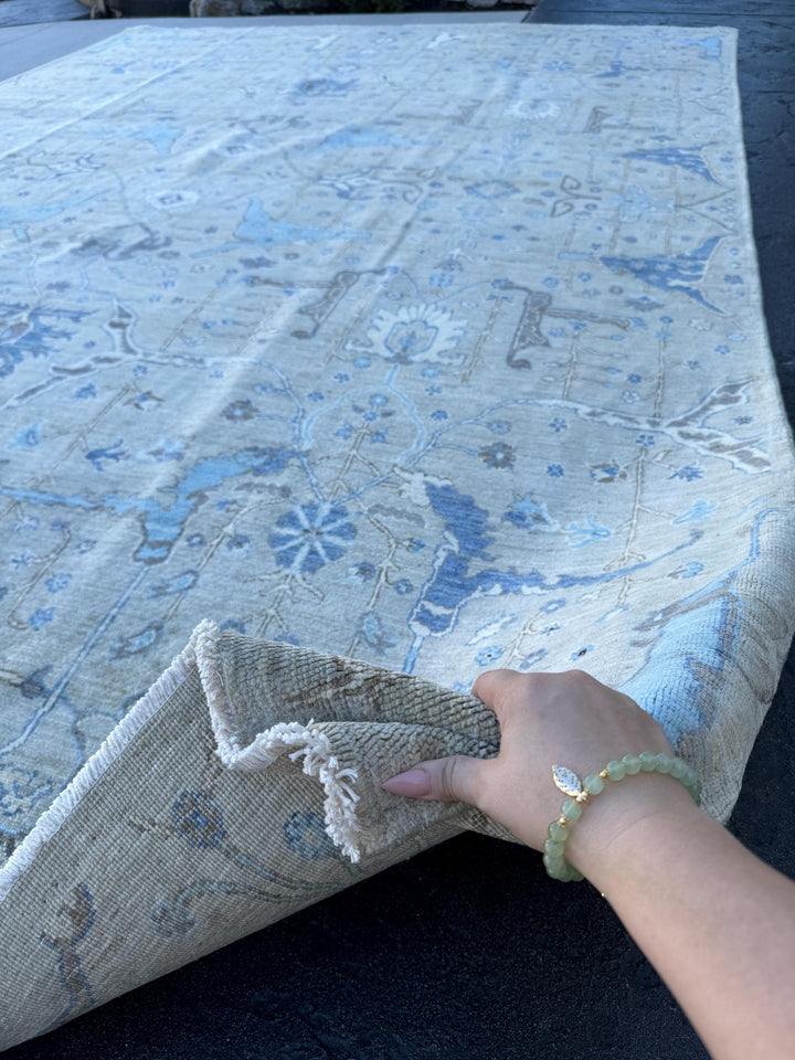 May include: A light blue and beige area rug with a floral and paisley design. The rug has a subtle distressed look, and the edges are frayed. The rug is made of a soft, plush material and is perfect for adding a touch of elegance to any room.