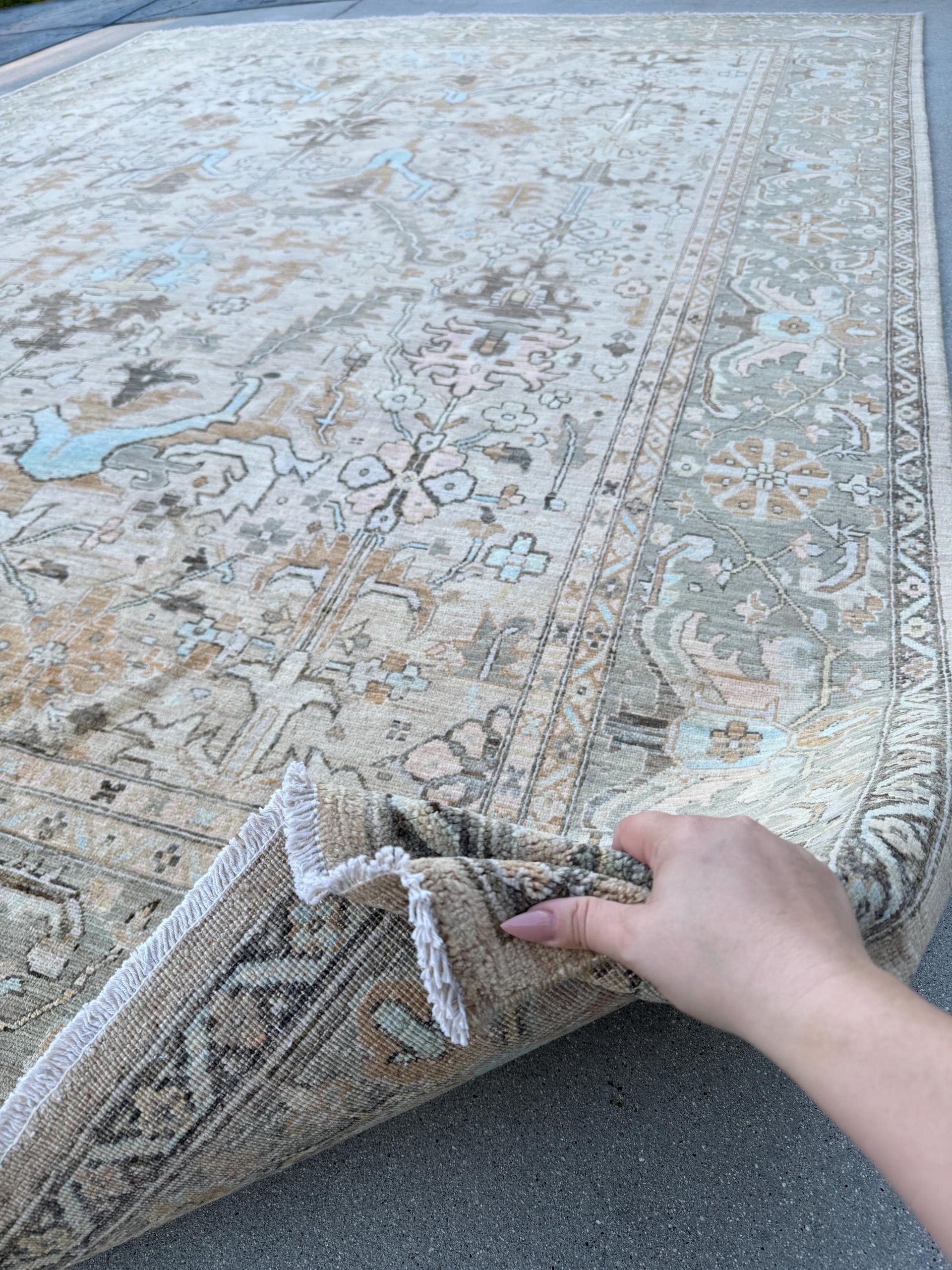 May include: A beige rug with a light blue and brown pattern. The rug has a fringe border and is folded in half.